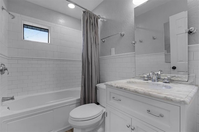 full bathroom with vanity, shower / bath combination with curtain, tile walls, and toilet