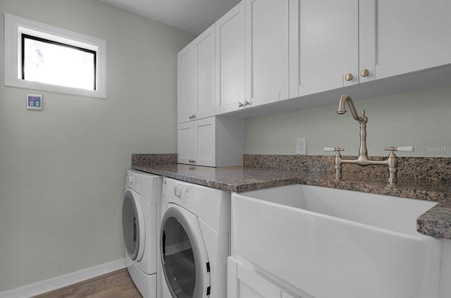 laundry room featuring washing machine and dryer, sink, cabinets, and hardwood / wood-style flooring