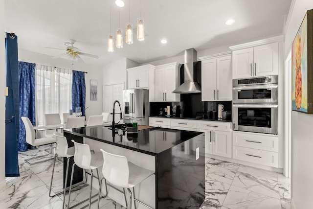 kitchen featuring a kitchen bar, appliances with stainless steel finishes, tasteful backsplash, and wall chimney exhaust hood