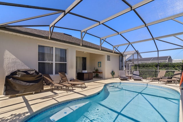 view of swimming pool featuring glass enclosure, a patio, and grilling area