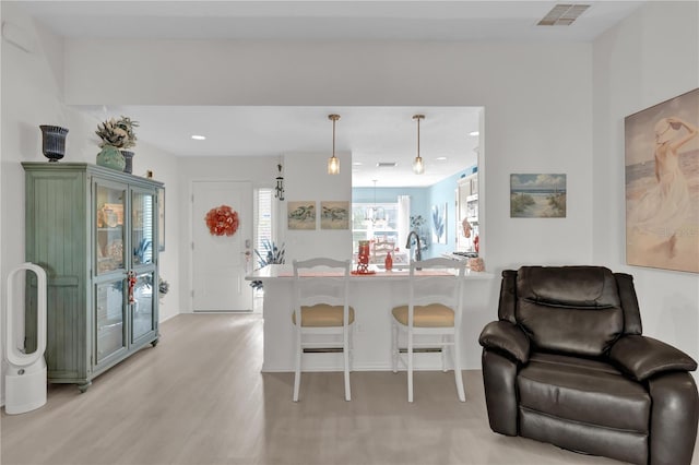 kitchen featuring a kitchen bar, kitchen peninsula, light hardwood / wood-style flooring, and pendant lighting