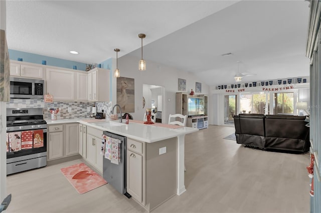 kitchen featuring kitchen peninsula, stainless steel appliances, sink, white cabinetry, and hanging light fixtures