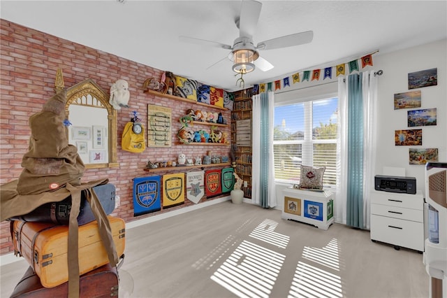 game room featuring ceiling fan and brick wall