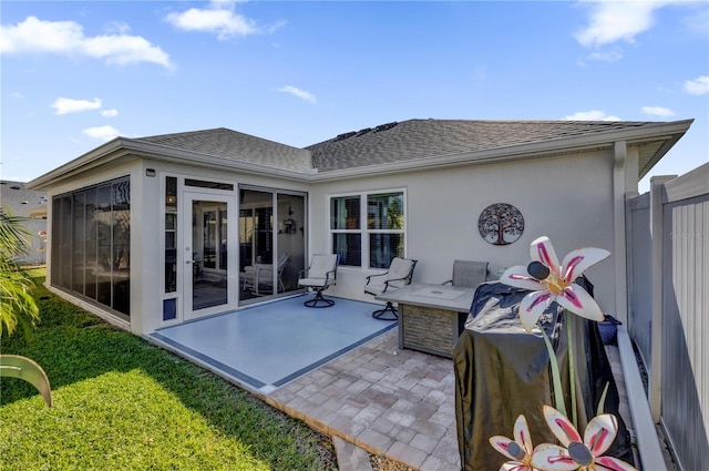 back of property with a patio, a lawn, and a sunroom