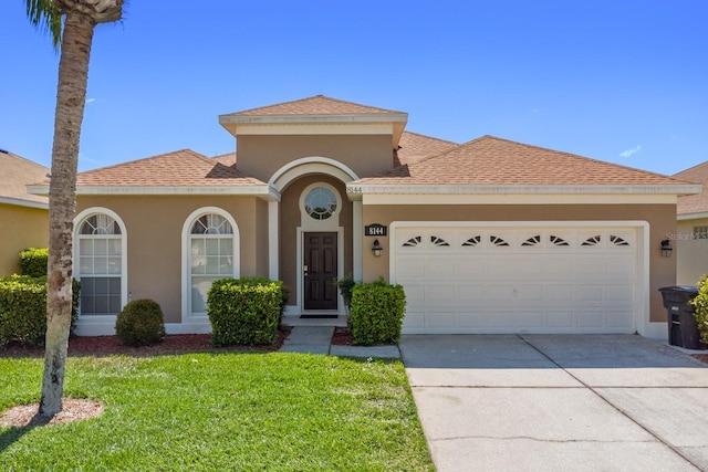 mediterranean / spanish house featuring a garage and a front lawn