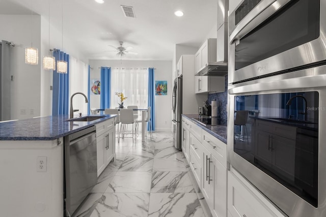 kitchen with white cabinetry, an island with sink, stainless steel appliances, and ceiling fan