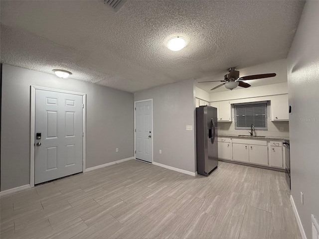 kitchen with white cabinetry, sink, ceiling fan, stainless steel refrigerator with ice dispenser, and a textured ceiling