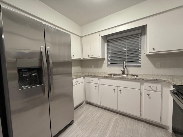 kitchen featuring light stone countertops, stainless steel appliances, white cabinetry, and sink