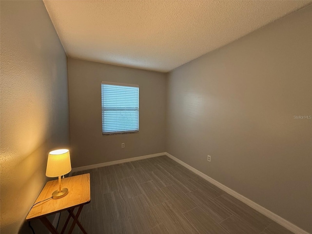 unfurnished room featuring dark hardwood / wood-style flooring and a textured ceiling