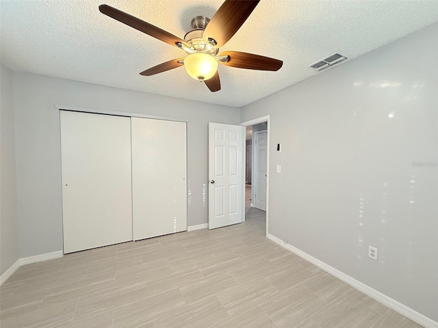 unfurnished bedroom with a textured ceiling, a closet, and ceiling fan