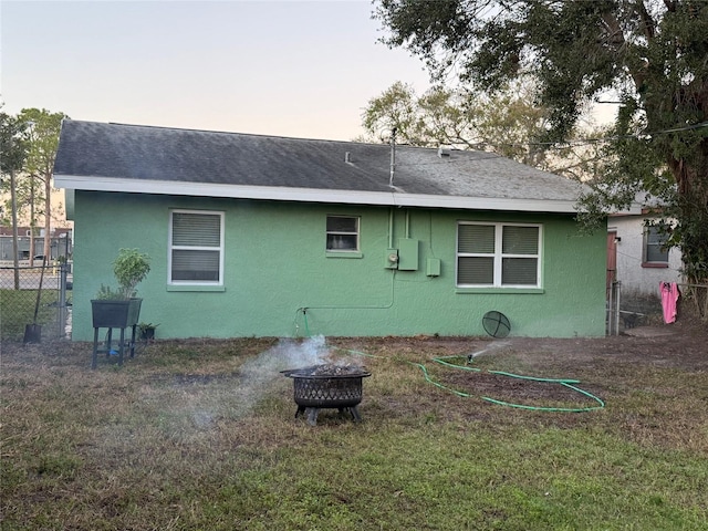 back house at dusk with a yard and an outdoor fire pit