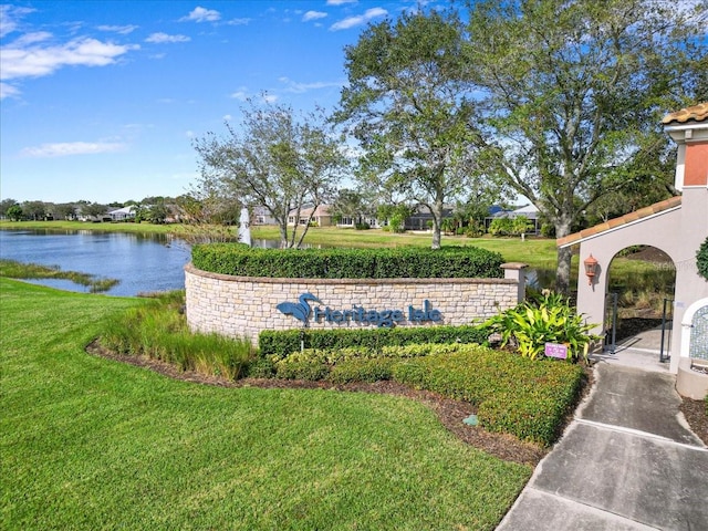 community sign with a lawn and a water view