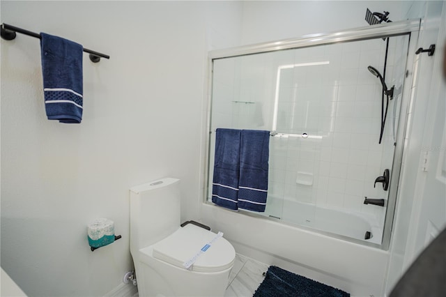 bathroom featuring toilet and combined bath / shower with glass door