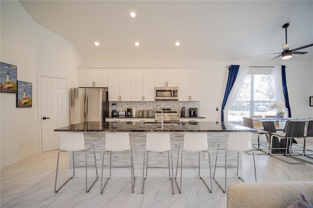 kitchen with sink, a spacious island, stainless steel appliances, and dark stone counters