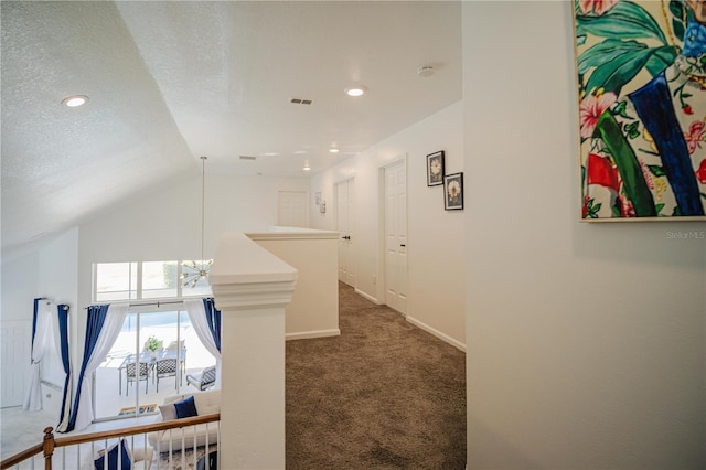 hallway featuring a textured ceiling, a chandelier, dark carpet, and vaulted ceiling