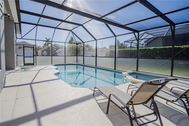 view of pool featuring glass enclosure, an in ground hot tub, and a patio