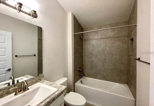 full bathroom featuring vanity, tiled shower / bath combo, and toilet