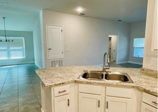 kitchen featuring white cabinetry, sink, kitchen peninsula, decorative light fixtures, and light tile patterned flooring