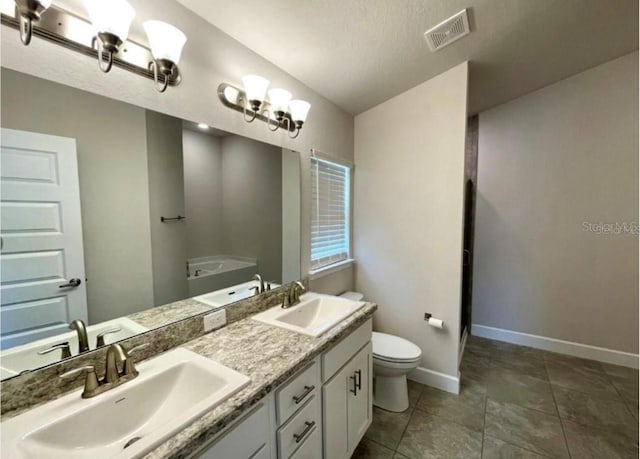 bathroom featuring vanity, a textured ceiling, and toilet