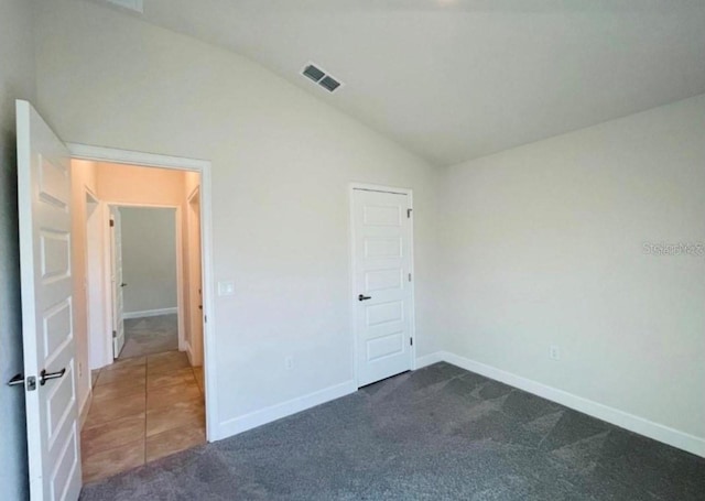 unfurnished bedroom with dark carpet and lofted ceiling