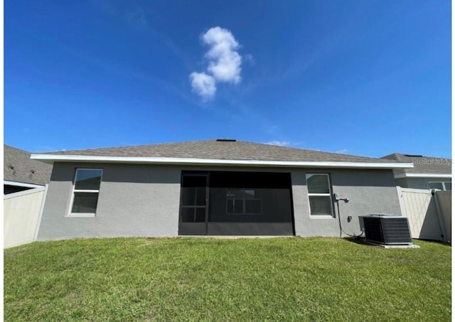 back of property featuring a sunroom, central air condition unit, and a yard