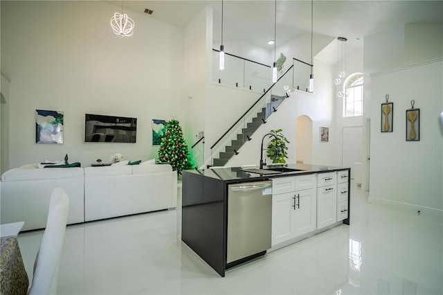 kitchen featuring dishwasher, sink, a towering ceiling, decorative light fixtures, and white cabinets