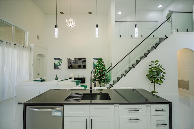 kitchen with a towering ceiling, sink, pendant lighting, dishwasher, and white cabinets