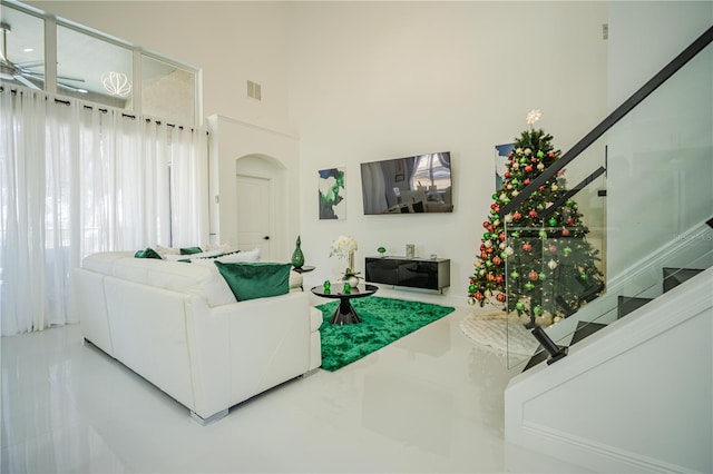 tiled living room featuring ceiling fan and a high ceiling