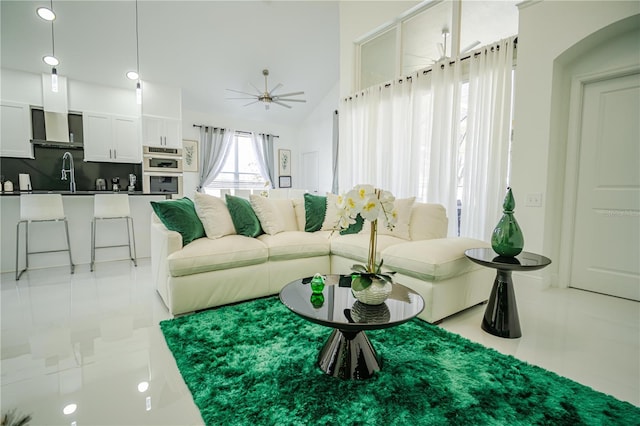 living room featuring ceiling fan, light tile patterned flooring, sink, and vaulted ceiling