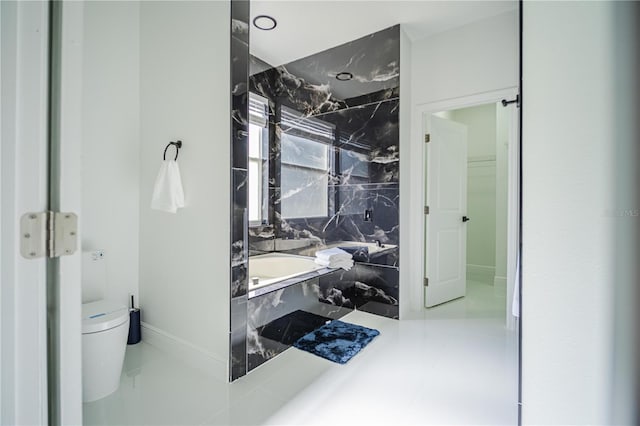 bathroom featuring tiled bath and toilet