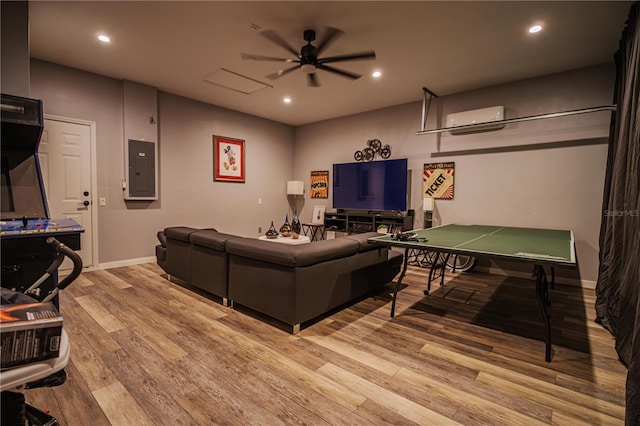 living room featuring a wall mounted air conditioner, ceiling fan, light wood-type flooring, and electric panel