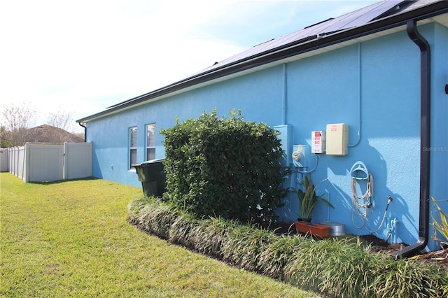 view of side of property featuring a yard and solar panels