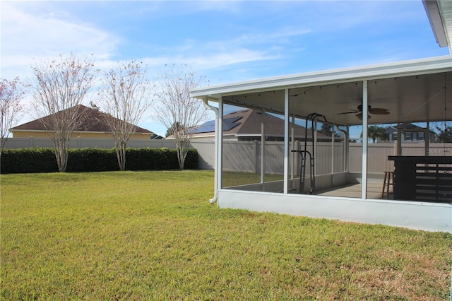 view of yard featuring a sunroom and ceiling fan