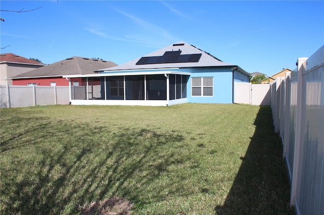 back of house with a sunroom, a lawn, and solar panels