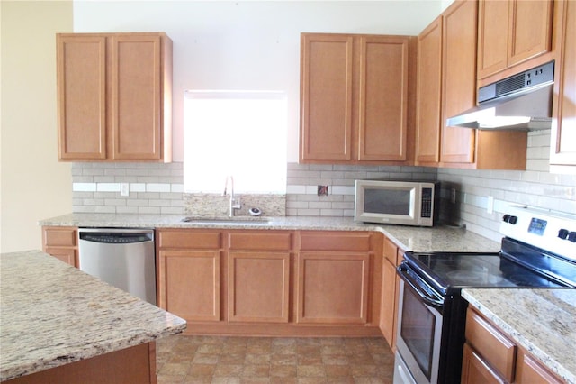 kitchen with light stone counters, sink, backsplash, and appliances with stainless steel finishes