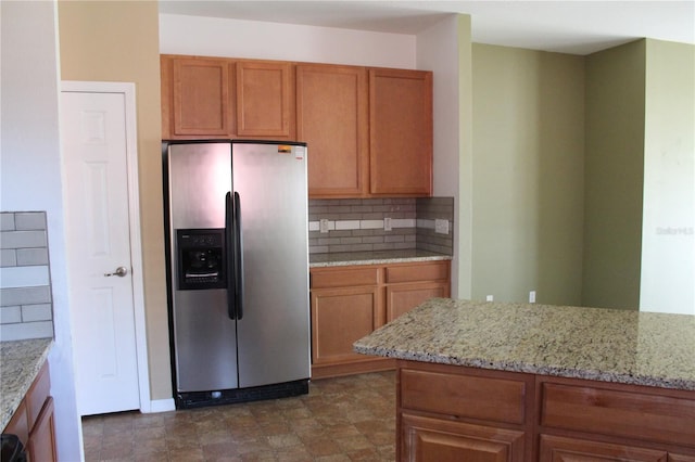 kitchen featuring tasteful backsplash, light stone counters, and stainless steel fridge with ice dispenser