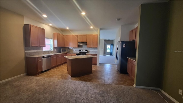 kitchen with appliances with stainless steel finishes, sink, a kitchen island, and backsplash