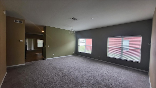 carpeted spare room with a notable chandelier