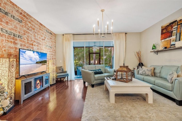 living room featuring dark wood-type flooring, brick wall, and a chandelier