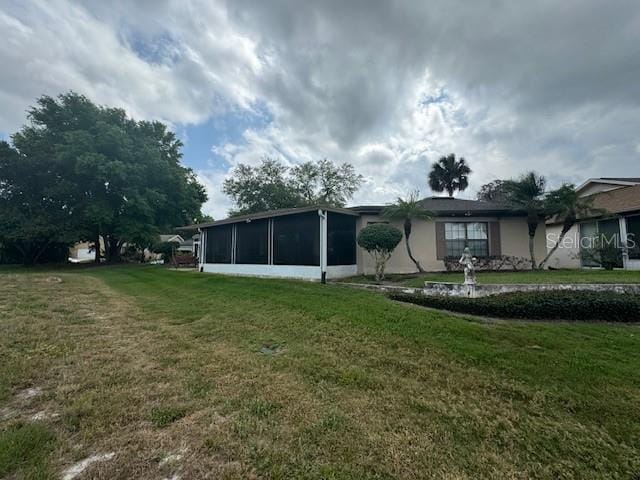 back of property with a sunroom and a lawn