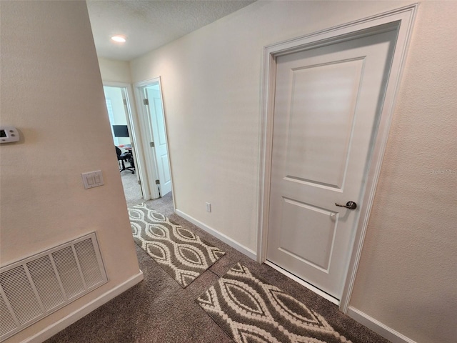 hallway with dark colored carpet