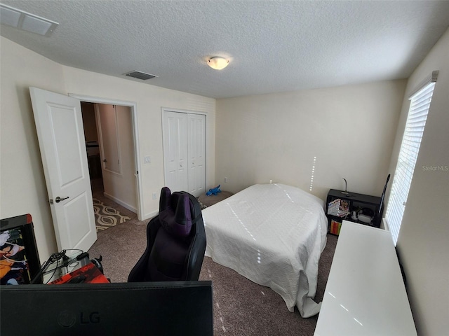 carpeted bedroom with a textured ceiling and a closet