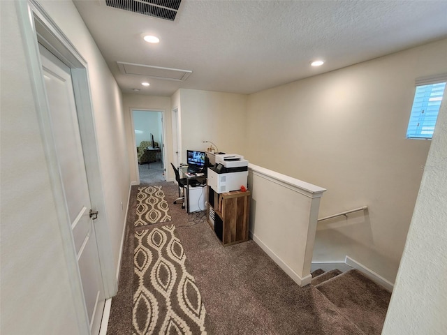 hall with a textured ceiling and dark carpet