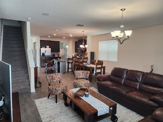 living room with a chandelier, wood-type flooring, and a textured ceiling