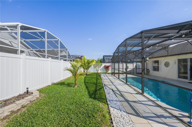 view of pool featuring a lawn and glass enclosure