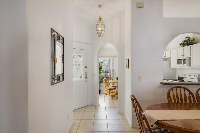 corridor featuring light tile patterned flooring and an inviting chandelier