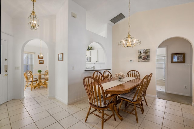 tiled dining area featuring a high ceiling and a notable chandelier