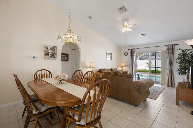 dining area featuring ceiling fan with notable chandelier, light tile patterned floors, and lofted ceiling