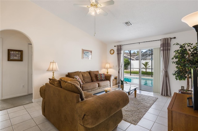 living room featuring ceiling fan, light tile patterned floors, and vaulted ceiling