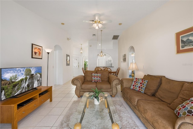 tiled living room with ceiling fan and a high ceiling